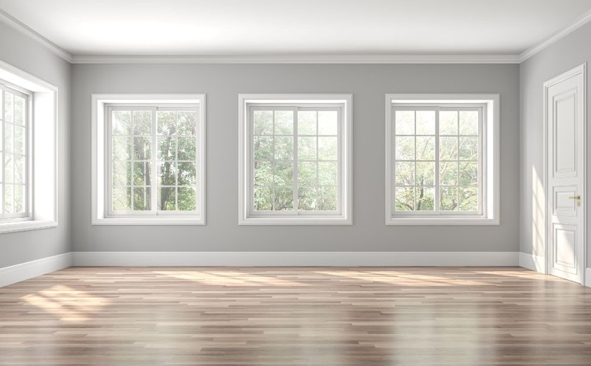 Empty room with wooden floor, gray walls, and white trim around the windows in Columbus, OH 