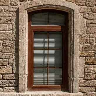 A brown-framed window with brown shutters on a stone building in Columbus, OH